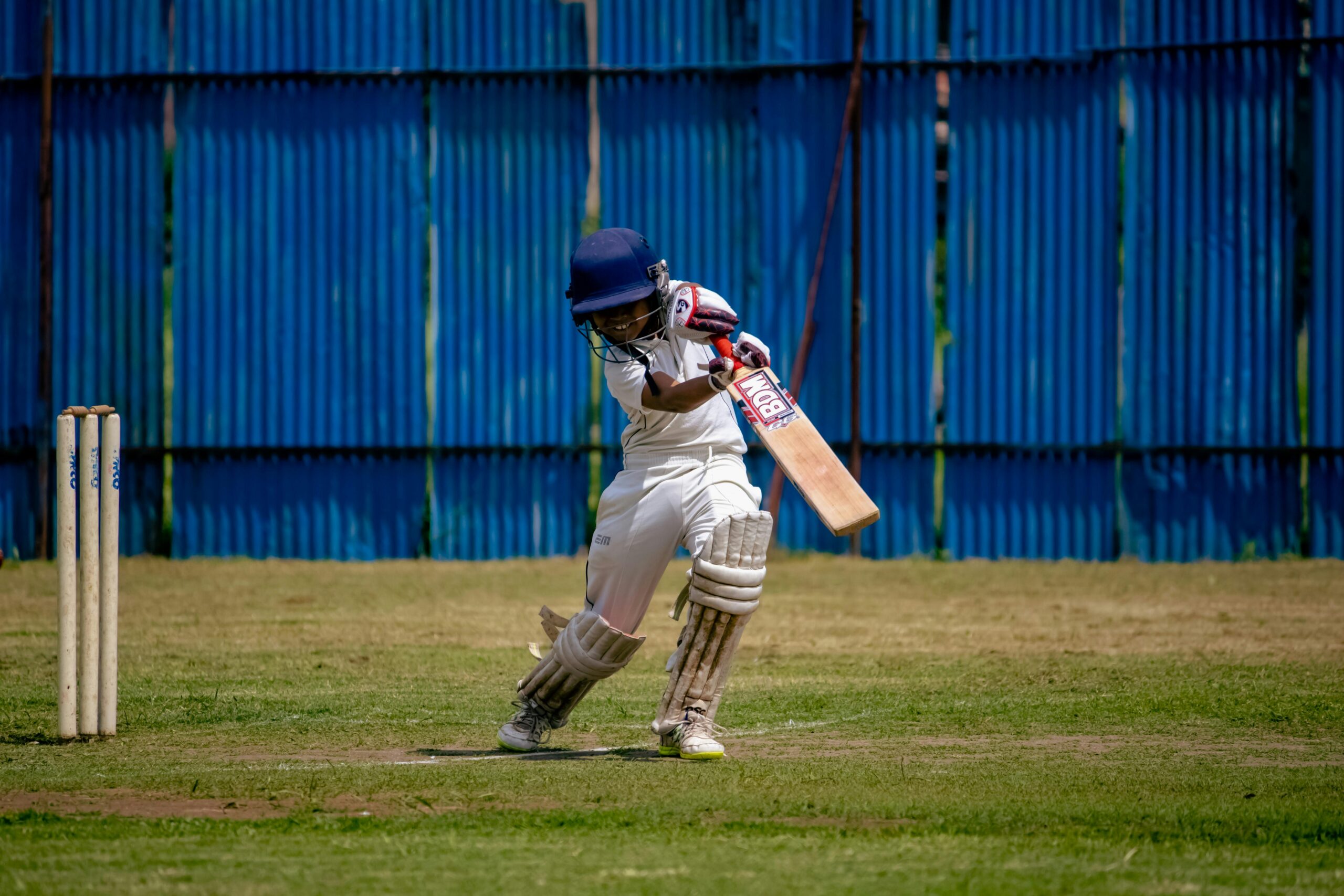 Young cricketer in action on a sunny day at a field in Gahunje, MH, India.